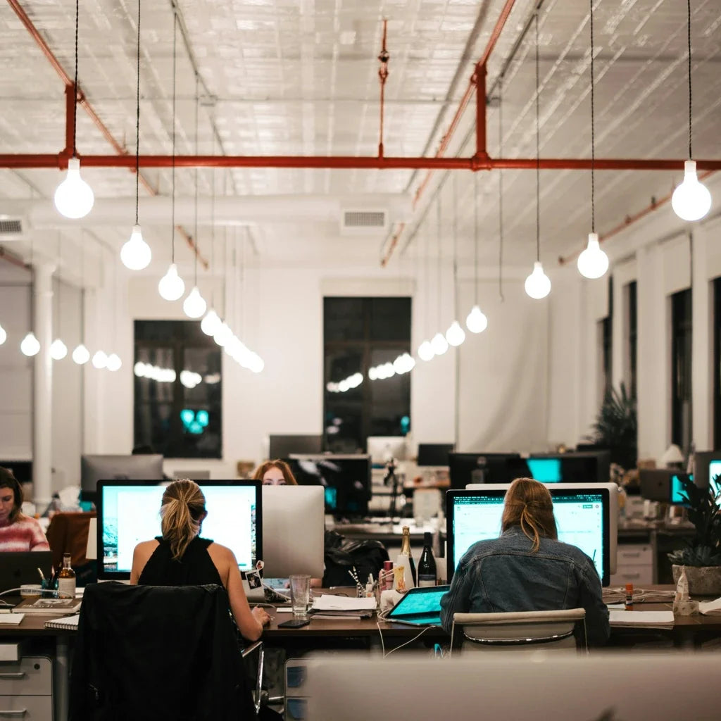 Open space de bureaux avec plusieurs salariés travaillant sur ordinateur, illustrant le thème des cadeaux salariés, des avantages en entreprise et de la réglementation URSSAF.